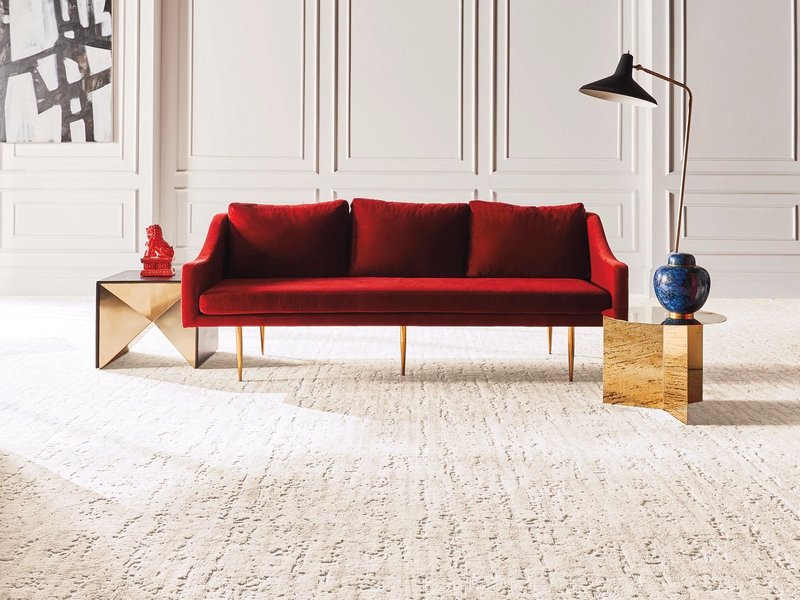 bright living room with a red velvet couch and cream colored textured carpet from Carpet Design Center in the Greenville, NC area